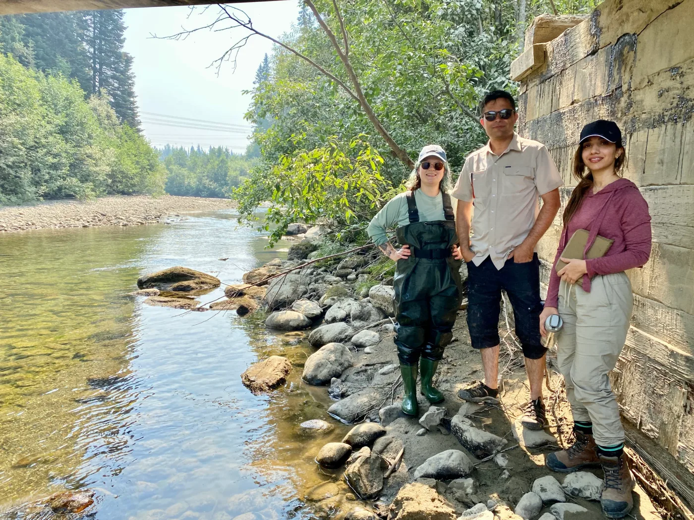 Behnoosh and two other people beside a river with a field notebook and waders