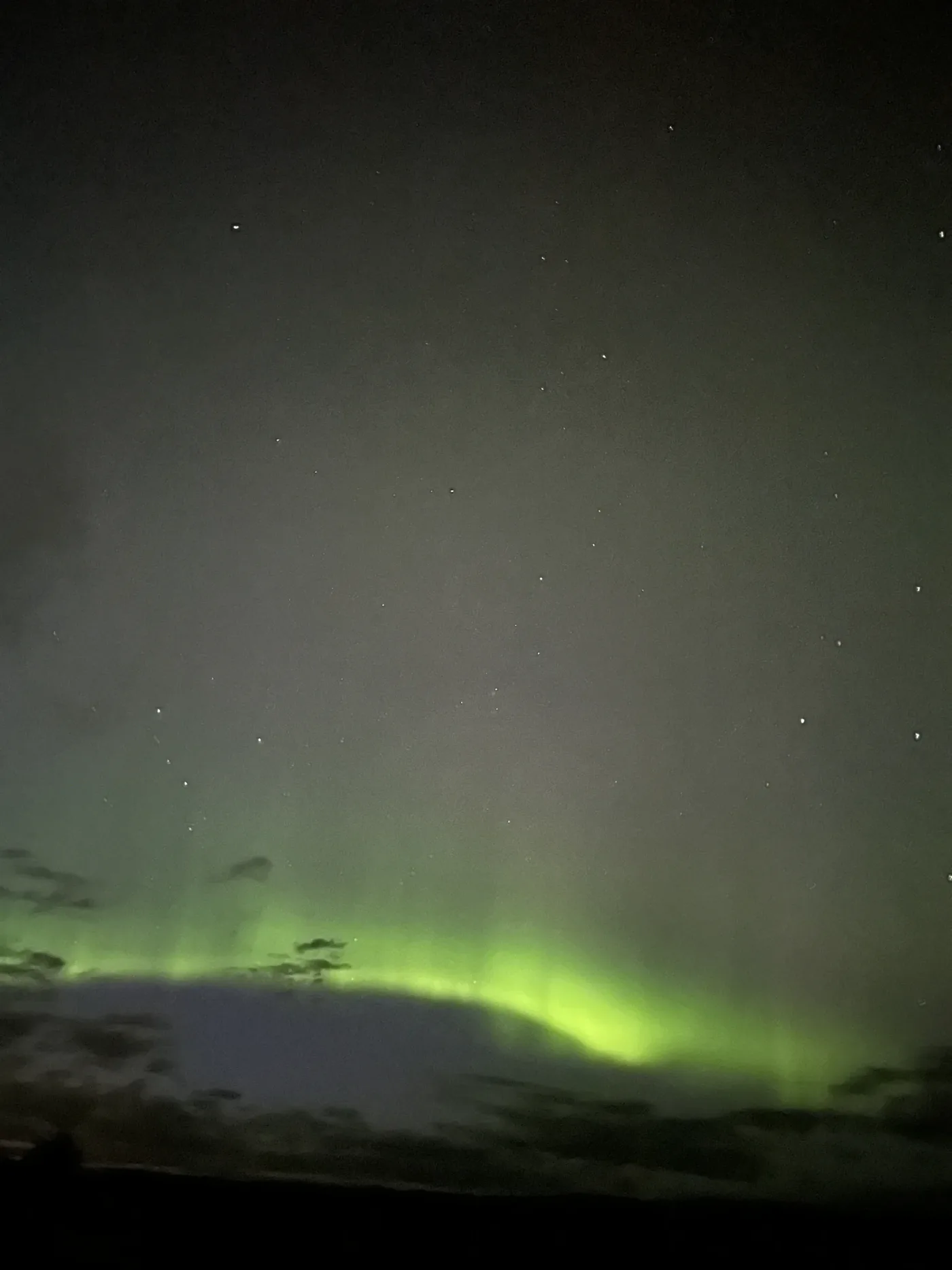 A sweep of green northern lights above a dark horizon.