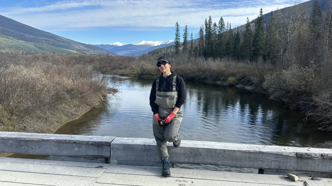 A personal photograph on a bridge with a river and autumn hills beyond.