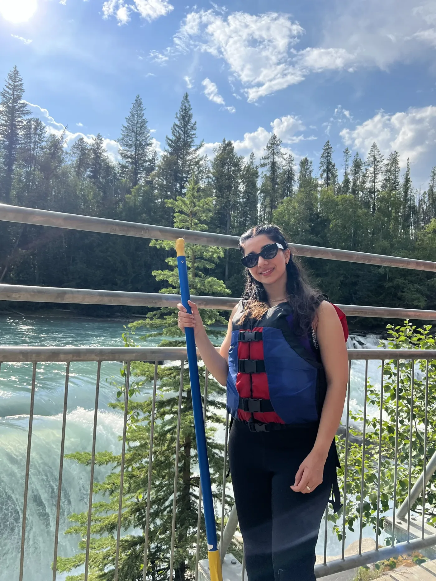 A personal portrait with a paddle beside a fast-flowing river.
