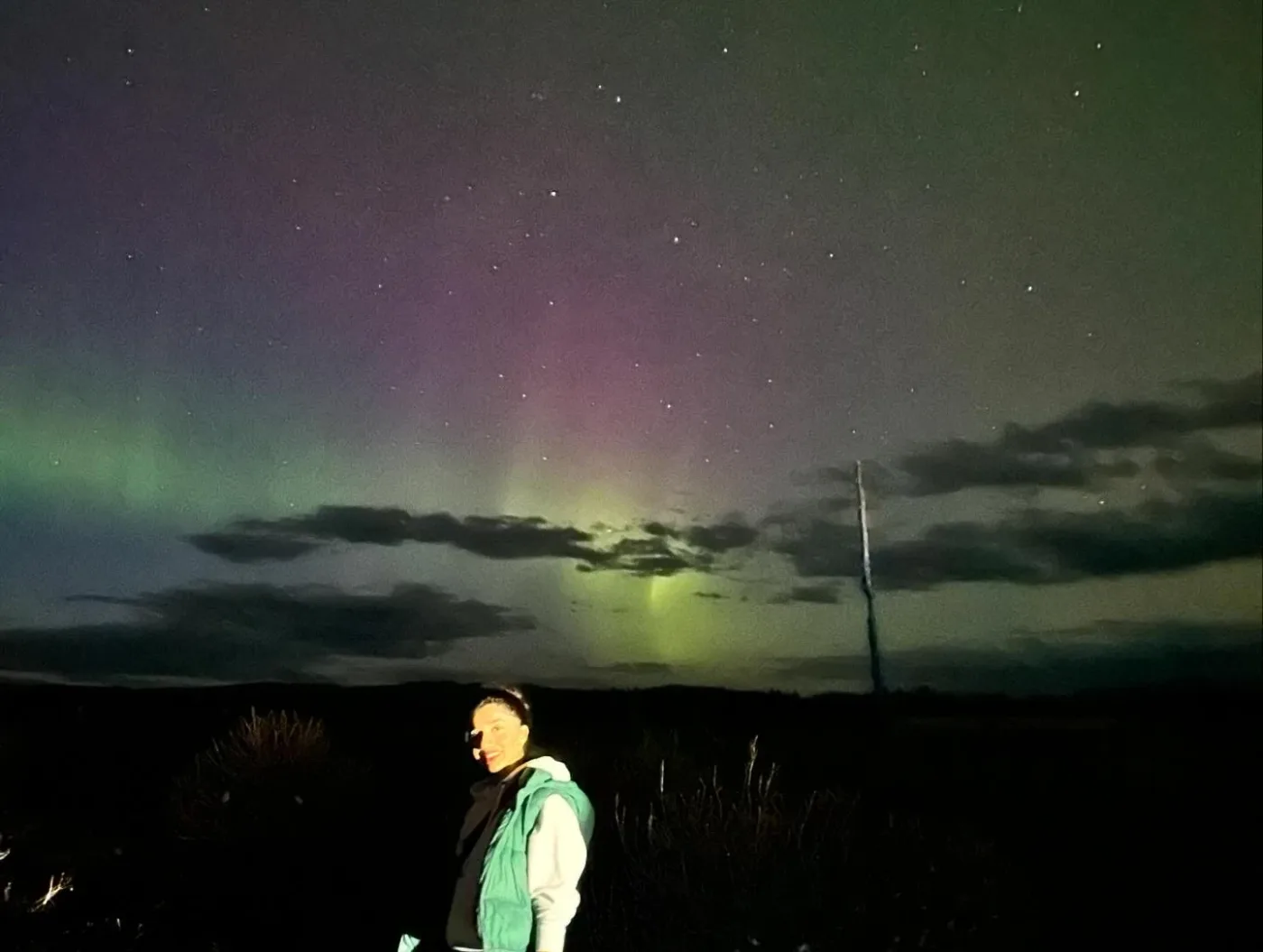 A personal photograph beneath a sky with green and purple northern lights.